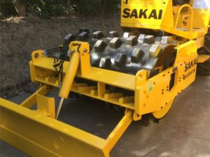 Sakai SV204TB compact soil roller with padfoot drum and hydraulic leveling blade or strike off blade kit.