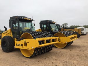 Two Sakai SV544D soil compactors shown with optional air conditioned operator cabs and padfoot or sheep foot shell kits.