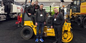 Amaco Equipment employees, sales manager, and president pose for a photo with a SAKAI TW354 combination asphalt roller at the 2026 National Heavy Equipment Show in Ontario Canada.