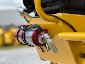 Optional factory installed 5lb ABC fire extinguisher and mount kit for the R2H-4 three wheel asphalt compactor mounted behind one of the operator seats. Shown from the trigger end.