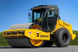 A SAKAI single drum soil compactor with 84" padfoot drum and a smooth shell kit. This photo showcases the optional air conditioned enclosed operator cab.