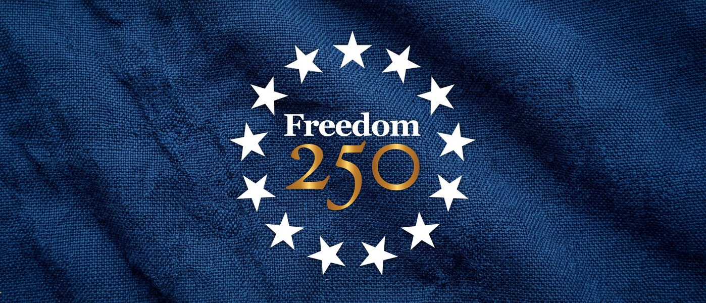 Freedom 250 icon logo over american flag textured navy blue fabric.