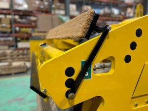 Side view of coco mat assembly mounted on a SAKAI SW774 66 inch 11 ton asphalt roller with mat in up position and scraper in up position.