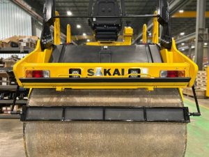 Rear view of Coco mat assembly mounted on a SAKAI SW774 66 inch 11 ton asphalt roller with mat in down position and scraper in up position.