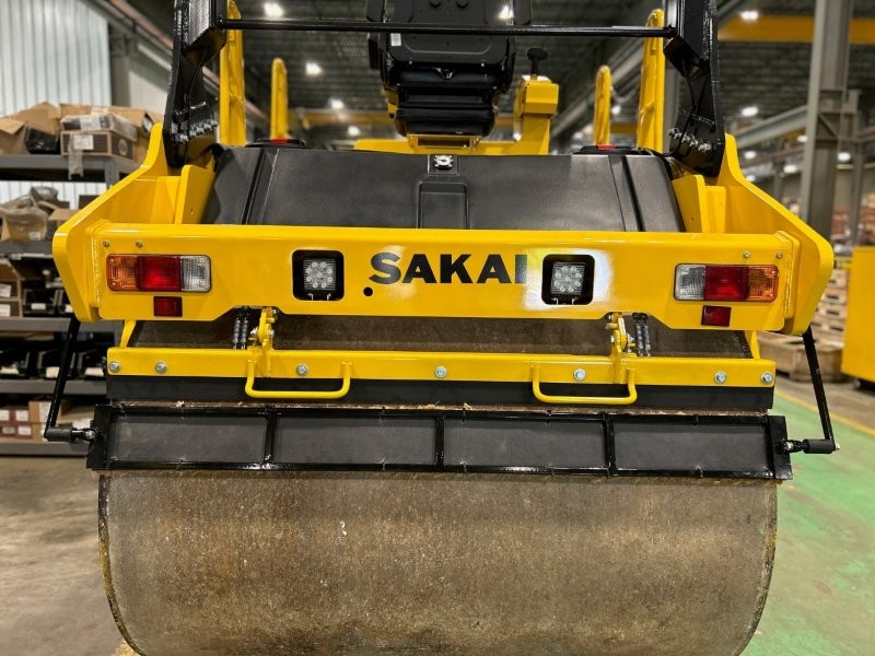 Rear drum view of coco mat assembly mounted on a SAKAI SW774 66 inch 11 ton asphalt roller with mat in down position and scraper in down position.