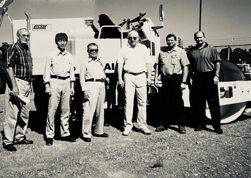 Sakai employees pose in front of large combination asphalt roller in Arkansas with first US dealer Clark Machinery Company.