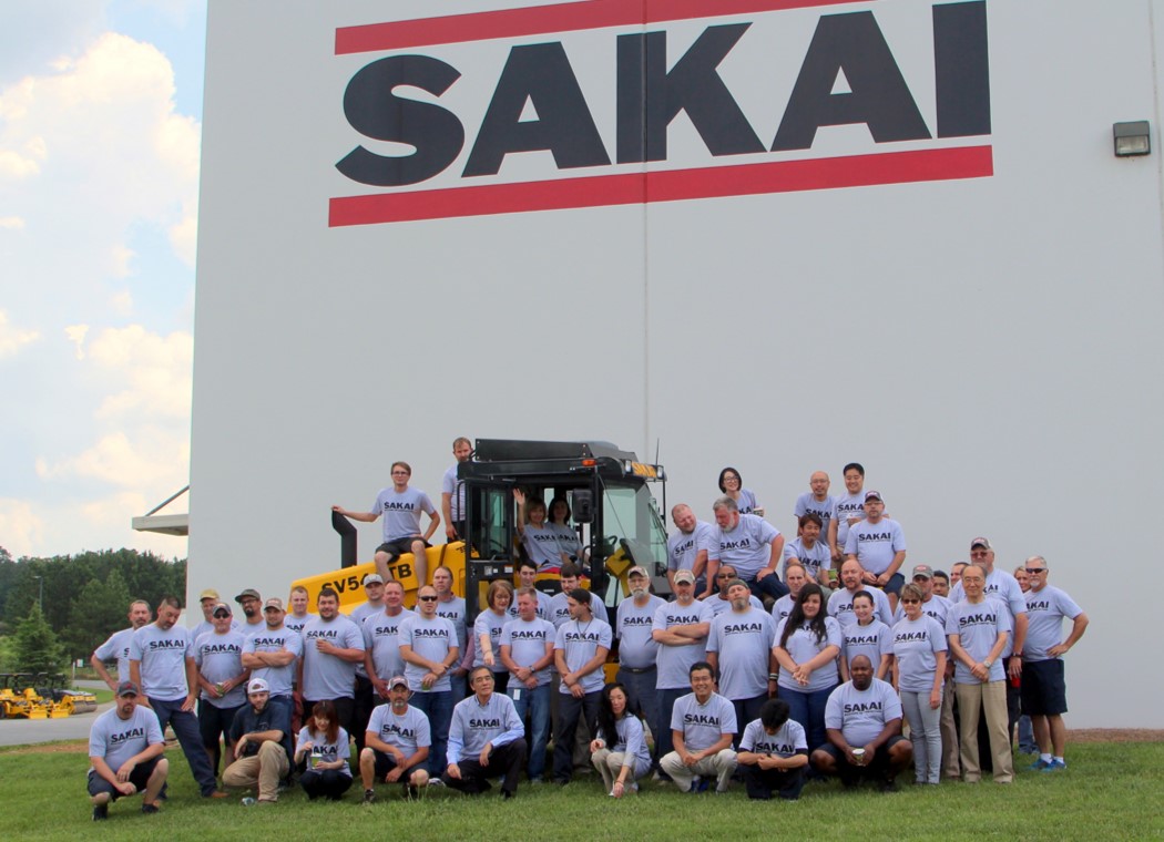 Sakai America employees post with an SV544 soil compactor