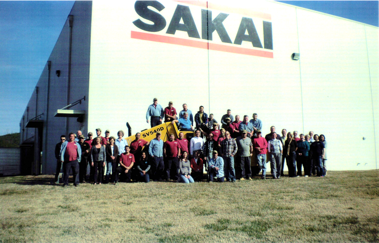 Sakai factory employees pose for a group photo with an SV540D smooth drum soil compactor in front of the Adairsville, Georgia production plant to celebrate 2000 machines built.