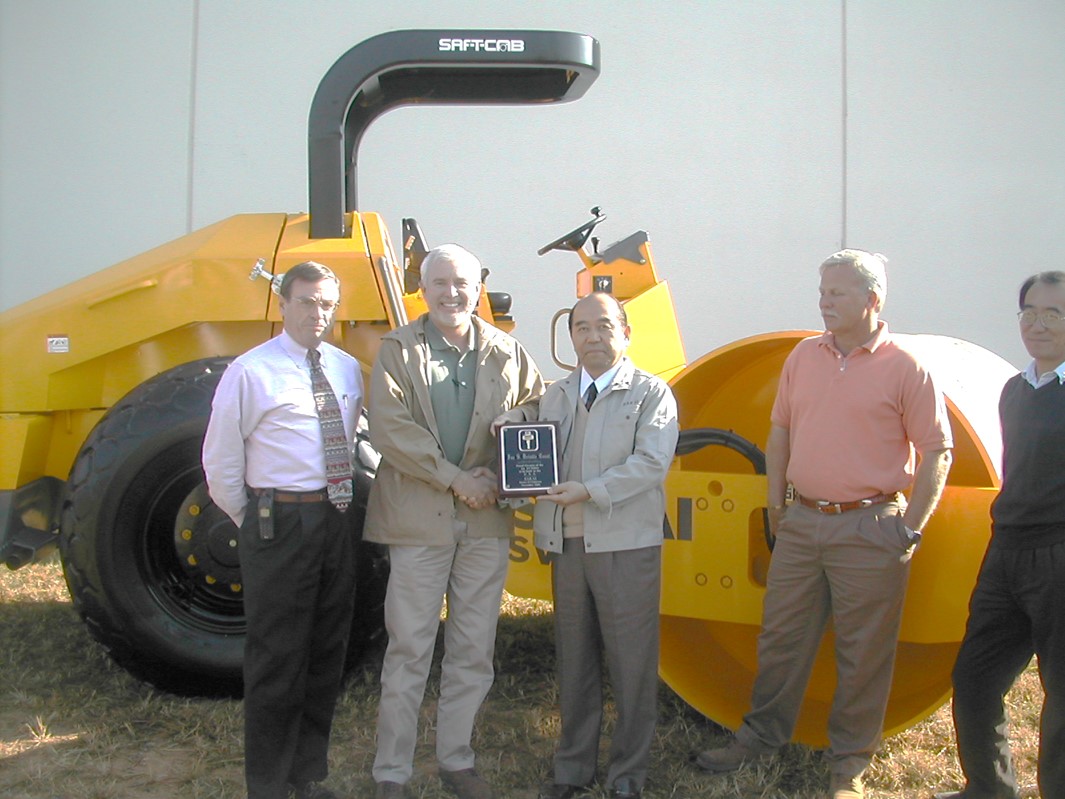 Historical photo of Sakai leadership handing key and plaque to the contractor (Fox Brindle) who purchased the first Sakai roller produced in the USA.