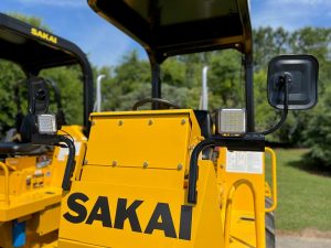 Front view of the optional mirror kit for the Sakai SV204 soil roller. Also shows optional LED work lights installed onto the mirror brackets.