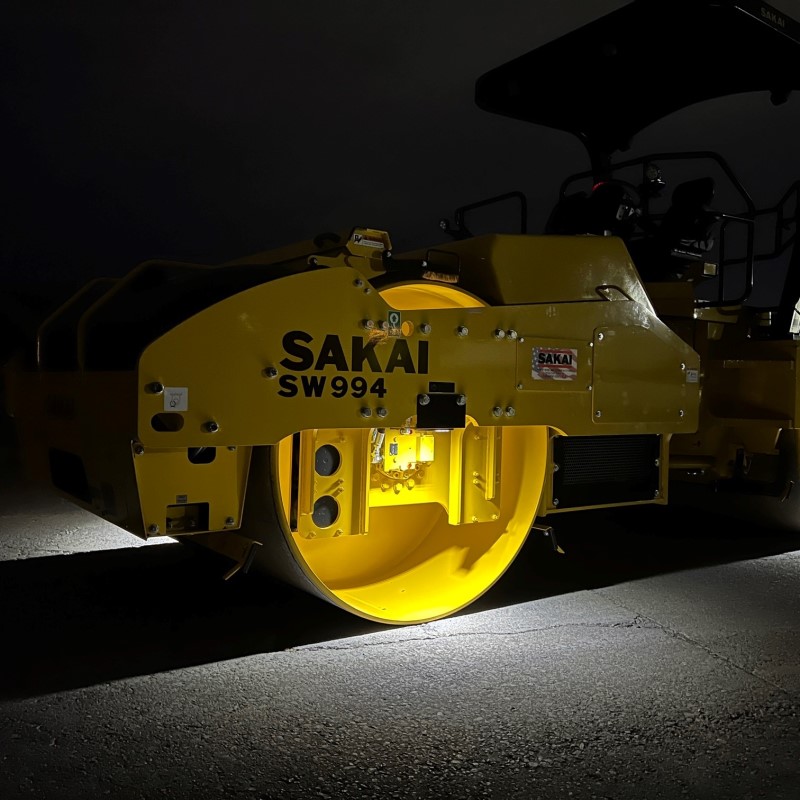 Close up of the sharp light cutoff produced by the LED drum light kit on a SAKAI 84" asphalt roller.