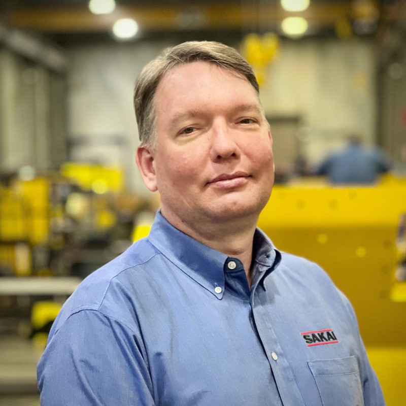 Sakai training and product support employee in front of the assembly line in our Adairsville, Georgia USA factory.